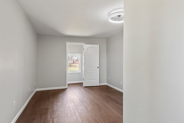 empty room with dark wood-type flooring and baseboards