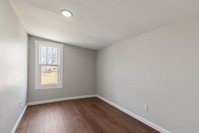 unfurnished room featuring visible vents, baseboards, and dark wood-style flooring