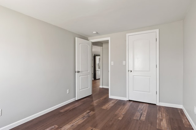 unfurnished bedroom with baseboards and dark wood-style flooring