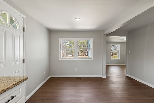 unfurnished dining area with visible vents, baseboards, and dark wood-style flooring