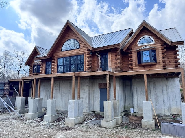 back of house featuring a standing seam roof, log siding, and metal roof