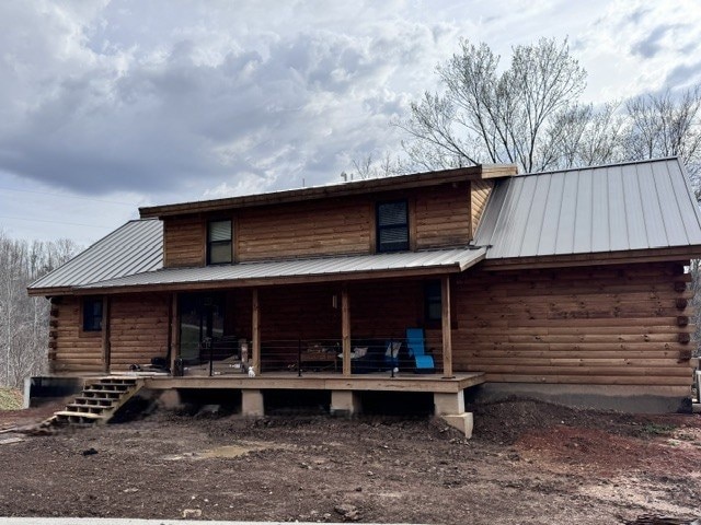 rear view of house with log siding, a porch, and metal roof