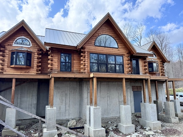 back of property with log exterior and metal roof