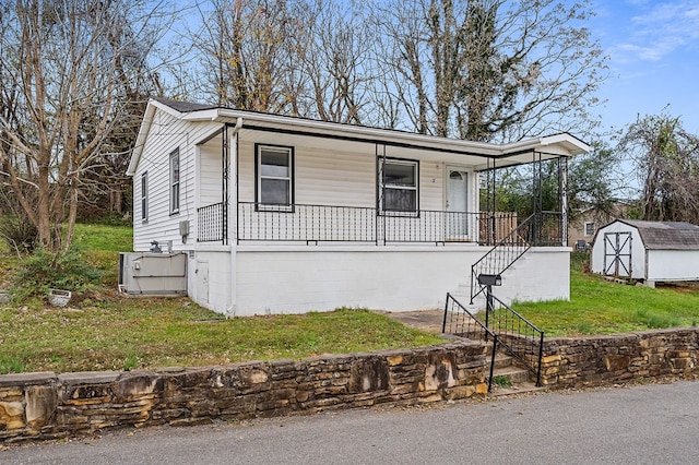 view of front facade featuring an outbuilding, a porch, a storage shed, a front lawn, and stairs