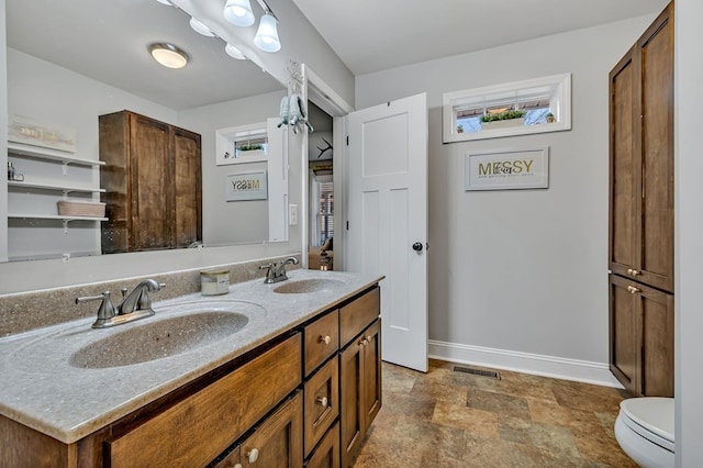 bathroom with double vanity, a sink, visible vents, and baseboards