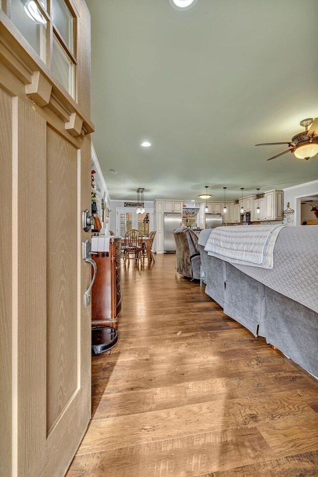 bedroom with stainless steel refrigerator, stainless steel built in refrigerator, and wood finished floors