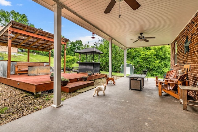 view of patio with an outbuilding, a storage unit, a hot tub, a ceiling fan, and a deck