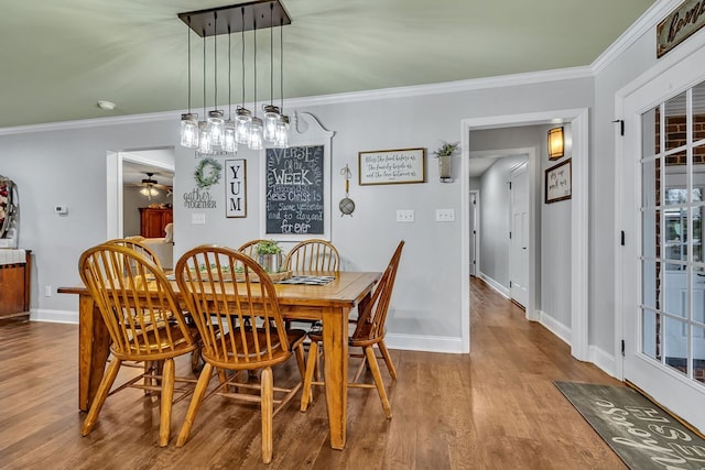 dining area featuring baseboards, ceiling fan, wood finished floors, and crown molding