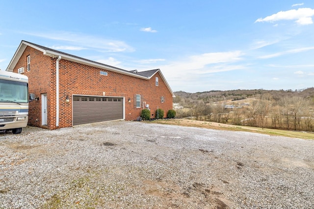 view of home's exterior featuring a garage, driveway, and brick siding