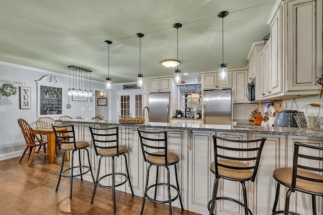 kitchen with appliances with stainless steel finishes, pendant lighting, a breakfast bar area, and dark stone counters