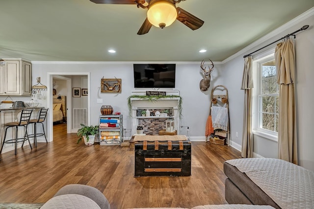 living room with baseboards, crown molding, visible vents, and wood finished floors