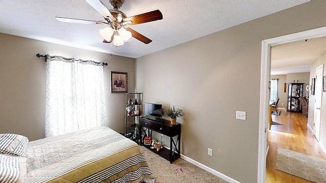 bedroom featuring ceiling fan, a textured ceiling, and baseboards