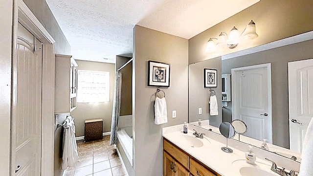 bathroom with a textured ceiling, a bathtub, a sink, and tile patterned floors