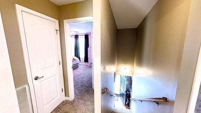 hallway featuring carpet floors, visible vents, and baseboards