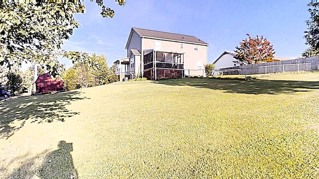 back of house featuring a lawn, fence, and a sunroom