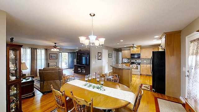 dining room with ceiling fan with notable chandelier, a textured ceiling, light wood-type flooring, and recessed lighting