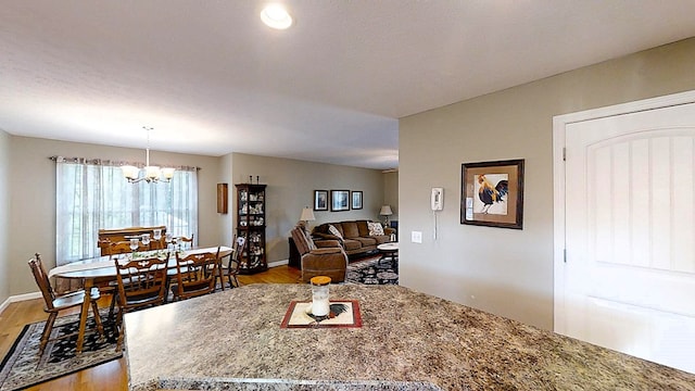 dining area featuring a chandelier, baseboards, and wood finished floors