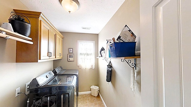 clothes washing area featuring light tile patterned floors, cabinet space, a textured ceiling, independent washer and dryer, and baseboards