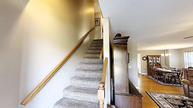 staircase featuring a notable chandelier and wood finished floors