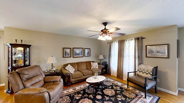 living area with light wood-type flooring, ceiling fan, and baseboards