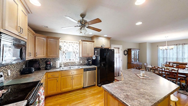 kitchen with light countertops, a kitchen island, a sink, and black appliances