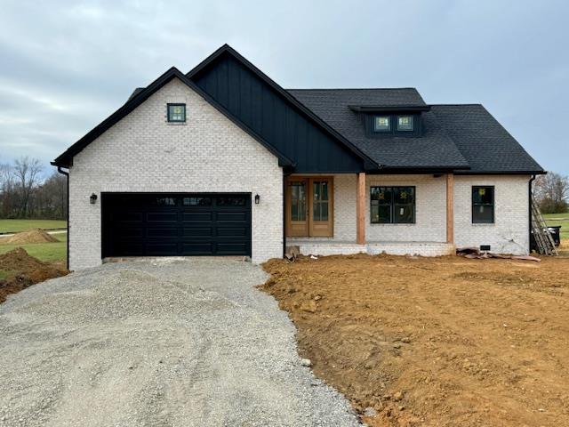 modern farmhouse style home featuring a garage, brick siding, driveway, and board and batten siding