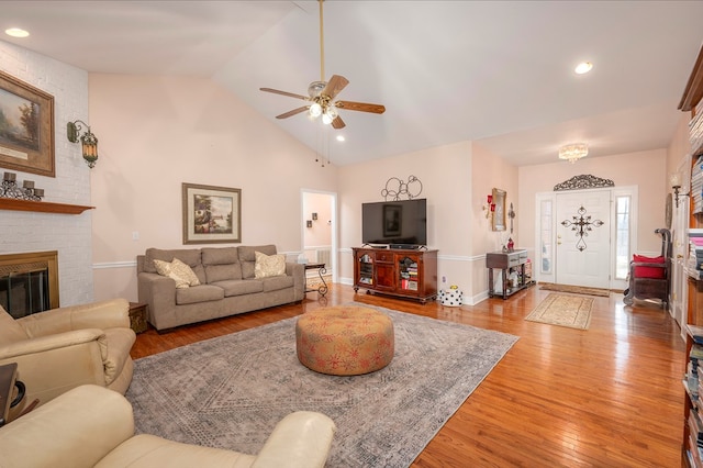 living room with light wood finished floors, ceiling fan, a brick fireplace, high vaulted ceiling, and recessed lighting