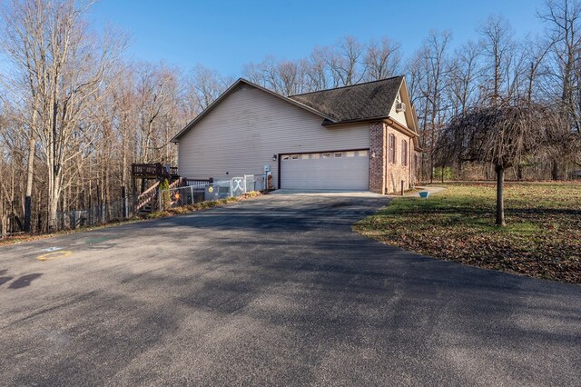 view of property exterior featuring a garage, brick siding, and driveway