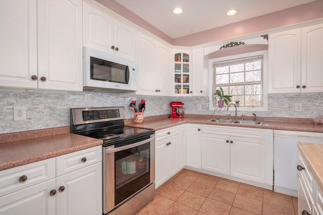 kitchen with glass insert cabinets, white appliances, white cabinetry, and a sink