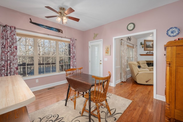 dining room with light wood-style flooring, a ceiling fan, visible vents, and baseboards