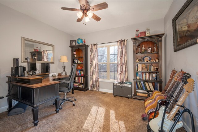 carpeted office space with a ceiling fan and baseboards