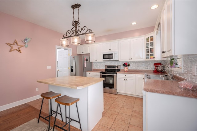 kitchen featuring stainless steel appliances, a sink, glass insert cabinets, and white cabinets