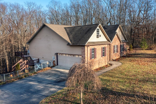 view of side of property featuring aphalt driveway, brick siding, a shingled roof, an attached garage, and fence