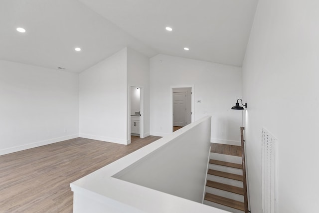 stairway with lofted ceiling, baseboards, wood finished floors, and recessed lighting