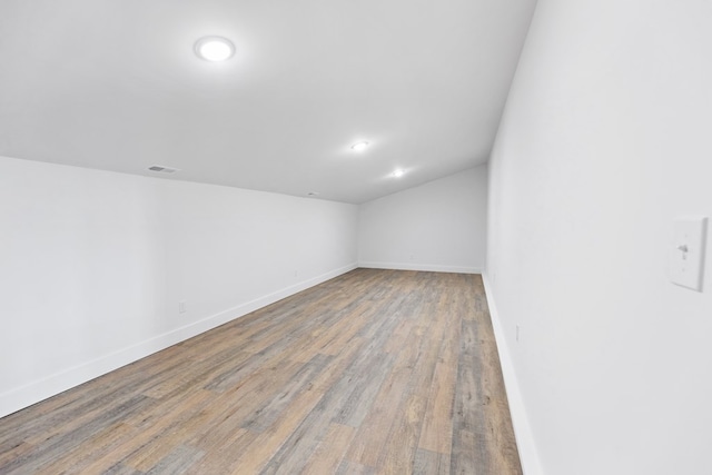 spare room with wood finished floors, visible vents, and baseboards