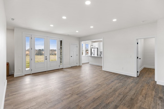 unfurnished living room with dark wood-style floors, recessed lighting, french doors, and baseboards