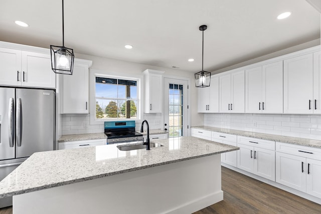 kitchen featuring a kitchen island with sink, stainless steel appliances, a sink, white cabinetry, and decorative light fixtures