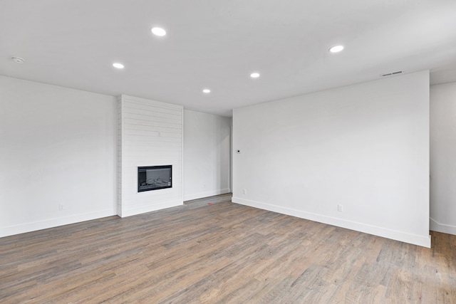 unfurnished living room featuring a large fireplace, dark wood-style flooring, visible vents, and recessed lighting