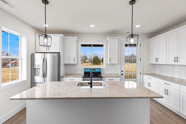 kitchen featuring hanging light fixtures, white cabinetry, a center island with sink, and appliances with stainless steel finishes