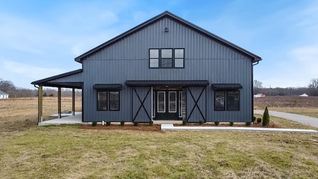 back of house with a standing seam roof, metal roof, and a yard