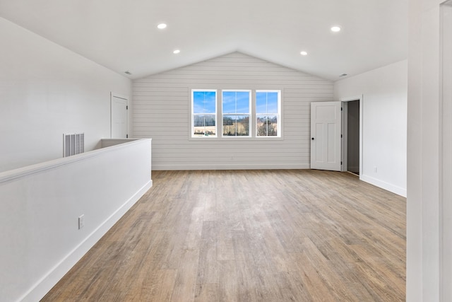 spare room with baseboards, visible vents, vaulted ceiling, light wood-style floors, and recessed lighting