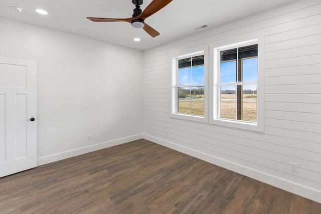 spare room with recessed lighting, dark wood-style flooring, a ceiling fan, visible vents, and baseboards