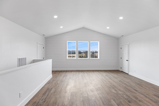 empty room featuring lofted ceiling, recessed lighting, dark wood-type flooring, visible vents, and baseboards