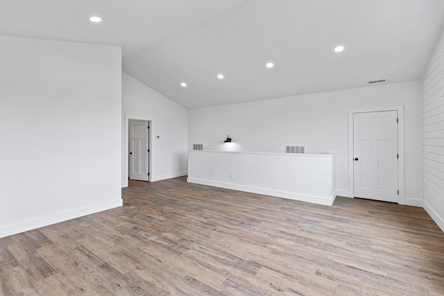 empty room featuring vaulted ceiling, wood finished floors, visible vents, and baseboards