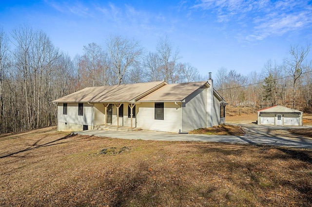 view of front of home with a detached garage, a porch, and an outbuilding