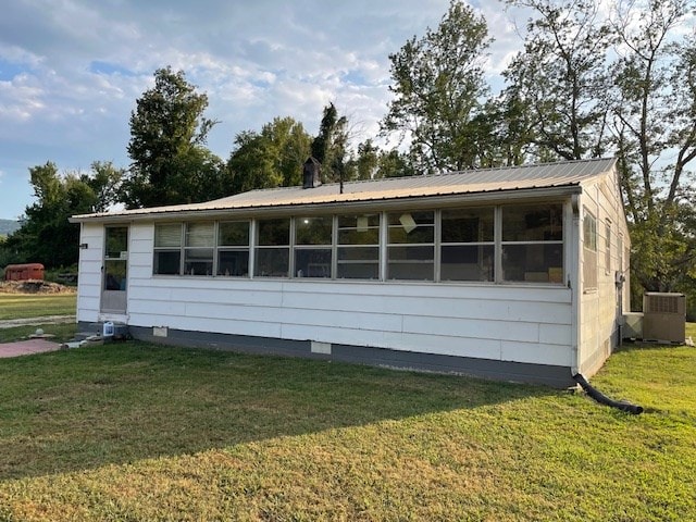 view of front of property featuring central AC unit, a front lawn, and metal roof