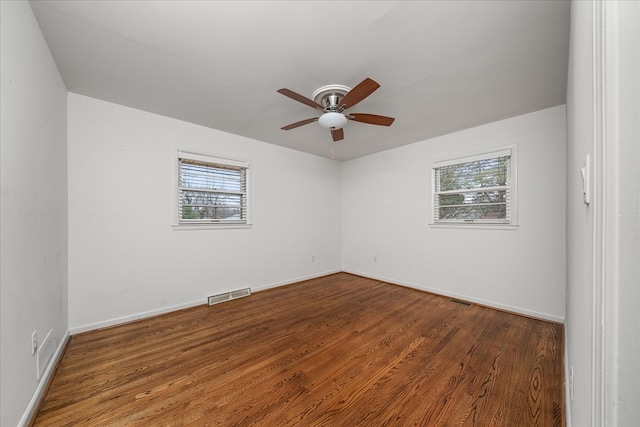 unfurnished room with a wealth of natural light, a ceiling fan, visible vents, and wood finished floors