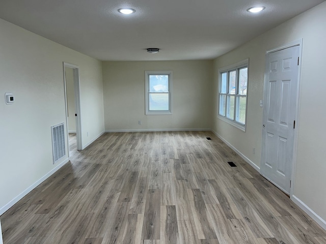 unfurnished room featuring visible vents, baseboards, and wood finished floors