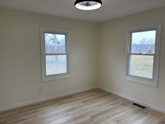 unfurnished room with light wood-style flooring, visible vents, and baseboards