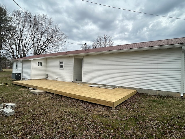 back of property with a wooden deck, central air condition unit, and metal roof